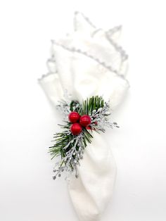 a white napkin with red berries and pine needles on it, sitting on a table