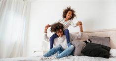 two girls jumping on the bed with their arms in the air