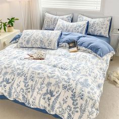 a bed with blue and white comforters in a bedroom next to a lamp on a nightstand