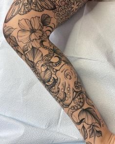 a woman's leg with tattoos and flowers on it