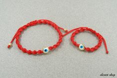 two red string bracelets with evil eyes on them