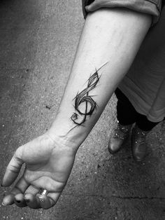 a black and white photo of a person's arm with a musical note tattoo on it