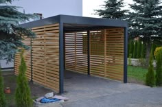 an outdoor covered area with wooden slatted screens on the sides and trees in the background