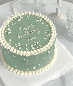 a green birthday cake sitting on top of a white table next to two wine glasses