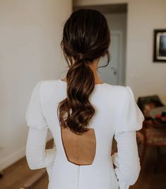 the back of a woman's white dress in a living room with wood floors