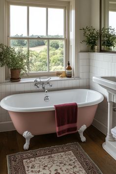 a pink bath tub sitting under a window next to a rug and sink in a bathroom