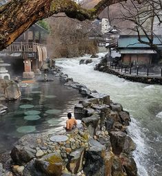 a person sitting on rocks in the middle of a river