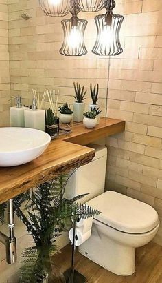 a white toilet sitting next to a wooden counter top in a bathroom under a light fixture