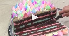 someone is cutting into a cake with colorful icing on the top and bottom layers