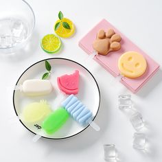 a white plate topped with popsicles and lemons on top of a table next to glasses