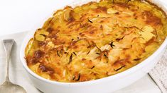 a casserole dish with potatoes and herbs in it on a white tablecloth