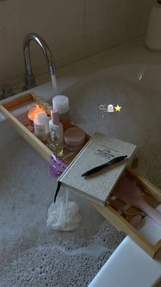 a bathtub with soap, candles and other personal care items on the tray in it