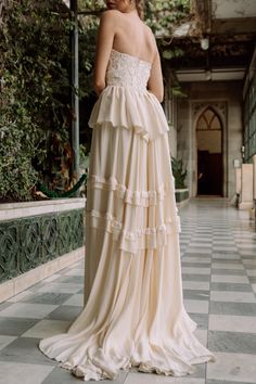 a woman in a white dress standing on a tiled floor with her back to the camera