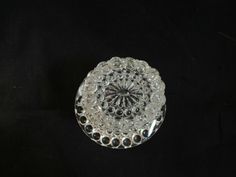 a clear glass dish on a black surface with circles around the base and center piece