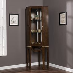 a tall wooden cabinet with glass doors on the front and bottom shelves in an empty room