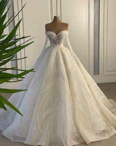 a wedding dress on display in front of a plant