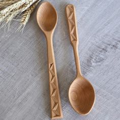 two wooden spoons sitting next to each other on top of a table with wheat