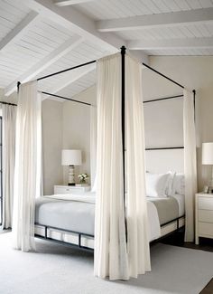 a bedroom with four poster bed and white drapes on the ceiling, along with two nightstands