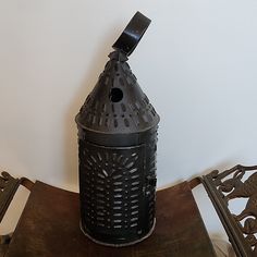 an old fashioned metal lantern sitting on top of a wooden table next to two iron chairs