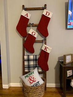 christmas stockings hanging on a ladder in the corner of a living room with plaid pillows