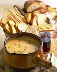 a bowl of soup with crackers and bread on the side