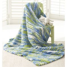 a crocheted blanket sitting on top of a chair next to a stuffed animal