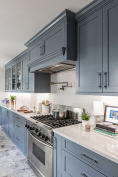 a kitchen with blue cabinets and white counter tops, an oven and stove top in the center