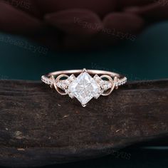 an engagement ring with three stones on top, sitting on a piece of drift wood