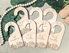 four wooden wedding date bookmarks on a table next to flowers and pearls, with two pairs of baby's shoes