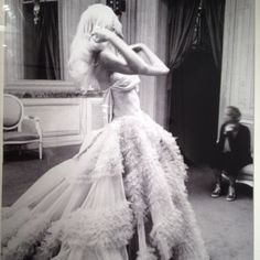 a black and white photo of a woman in a dress with feathers on the skirt