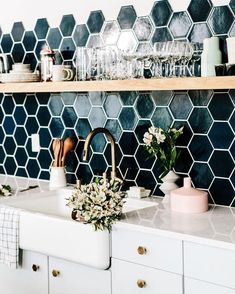 a kitchen sink with wooden utensils and dishes on the shelf above it in front of a blue tiled backsplash