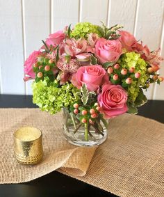 a vase filled with pink and green flowers on top of a table