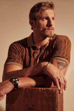 a man sitting on top of a wooden box with his arms crossed and looking off to the side