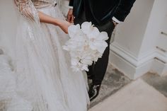 a bride and groom standing next to each other in front of a doorway holding flowers