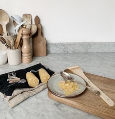 a table topped with wooden utensils and bowls filled with food sitting on top of a cutting board