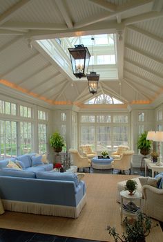 a living room filled with lots of furniture under a glass ceiling covered in light colored windows