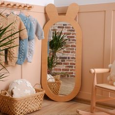 a room with a mirror, potted plant and sweaters hanging on the wall