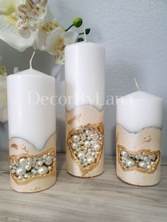 three candles are decorated with pearls and glitters on the top one has a heart