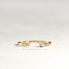 a yellow gold ring with two diamonds on the top and bottom, sitting on a white surface