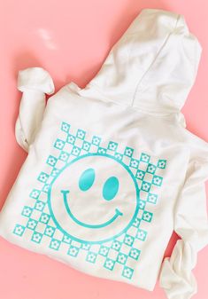 Woman & Girl Sweater | Girls Sweatshirt | Adult Sweater | Mama Sweatshirt | Smiley Face Sweater  Gildan Unisex Adult/Youth Heavy Cotton Long Sleeve Sweatshirt, it has a design in Black HTV (Heat Transfer Vinyl) Design: Front: Smiley face (pocket size) Back: Checkered Smiley face  Important: The dimensions of the designs will be proportional to the size of the Sweater. Available Sweatshirt colors:   - White    - Sport Grey     - Black   Details: The Gildan 18000 Adult Sweatshirt is made from a he Playful Cotton Hoodie With Graphic Print, Playful White Long Sleeve Sweatshirt, Playful White Sweatshirt For Loungewear, White Hooded Top With Screen Print, Playful White Sweatshirt For Fall, White Screen Print Tops For Winter, Winter White Tops With Screen Print, Winter White Screen Print Tops, Playful Hoodie With Graphic Print For Spring