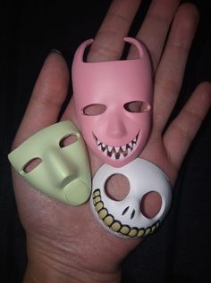 three different types of masks in the palm of someone's hand, one pink and one green