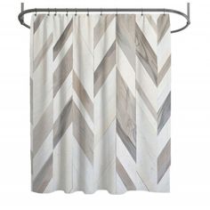 a white shower curtain with grey and brown chevrons on it, hanging from a metal rod