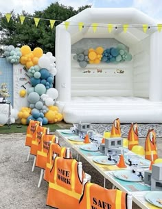 an outdoor party with balloons and decorations on the table, along with yellow and blue napkins