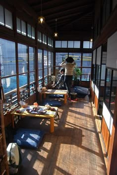 a person standing on top of a wooden floor next to tables and windows in a building