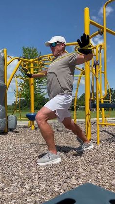 a man is running in front of a yellow playground structure with swings and climbing equipment