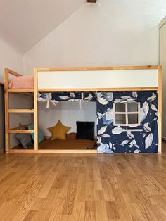 a bunk bed with blue and white wallpaper in an attic bedroom, next to a wooden floor