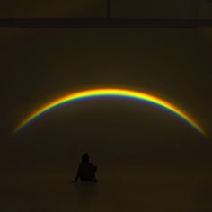 a person sitting on the floor in front of a rainbow