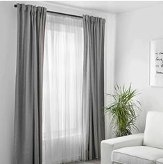 a living room with a white couch and grey drapes in front of a window