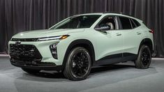 a white suv is on display at an auto show in front of a curtained background