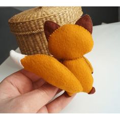 a hand holding a small stuffed animal in front of a basket